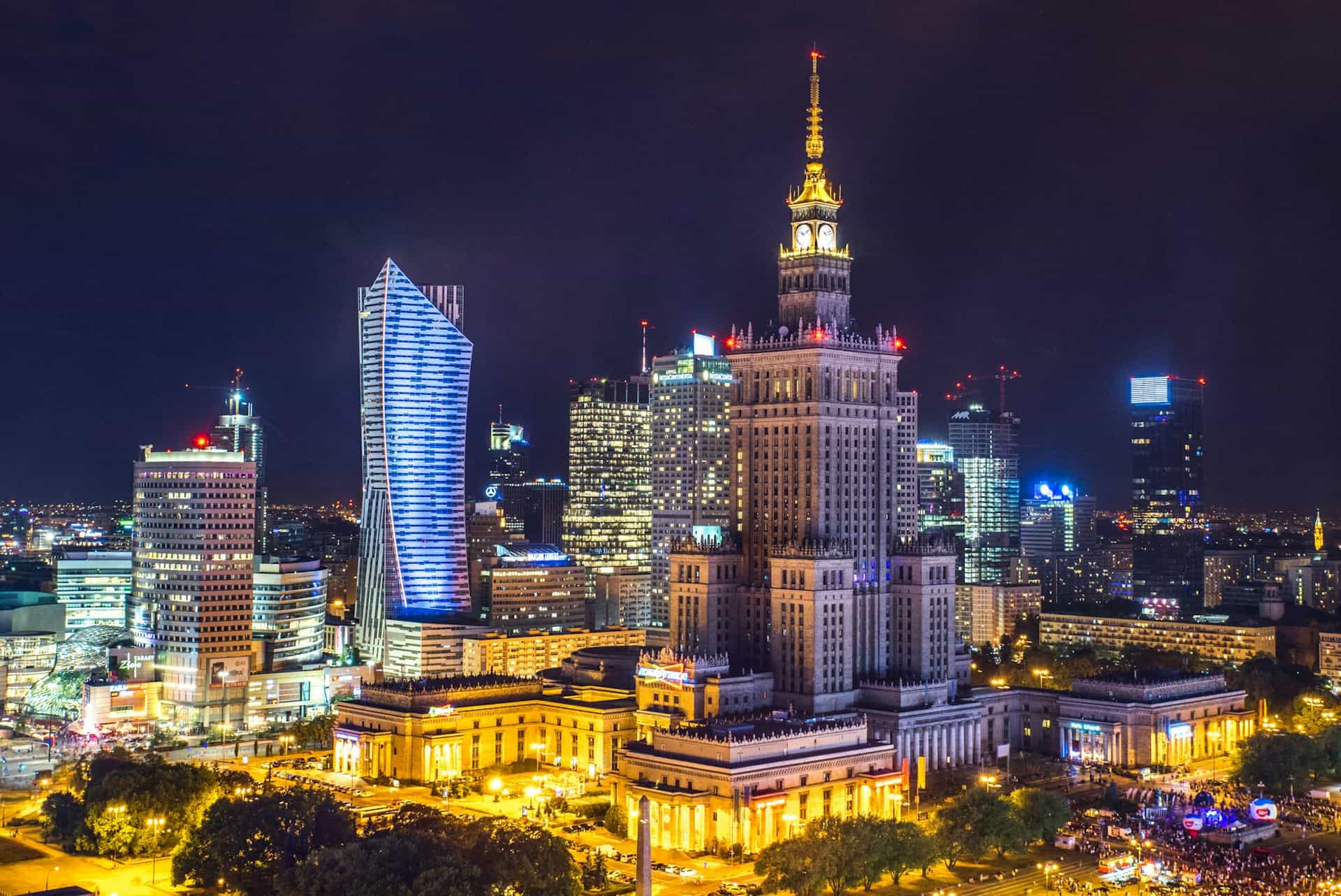 The illuminated Palace of Culture and Science surrounded by Warsaw's modern skyline at night