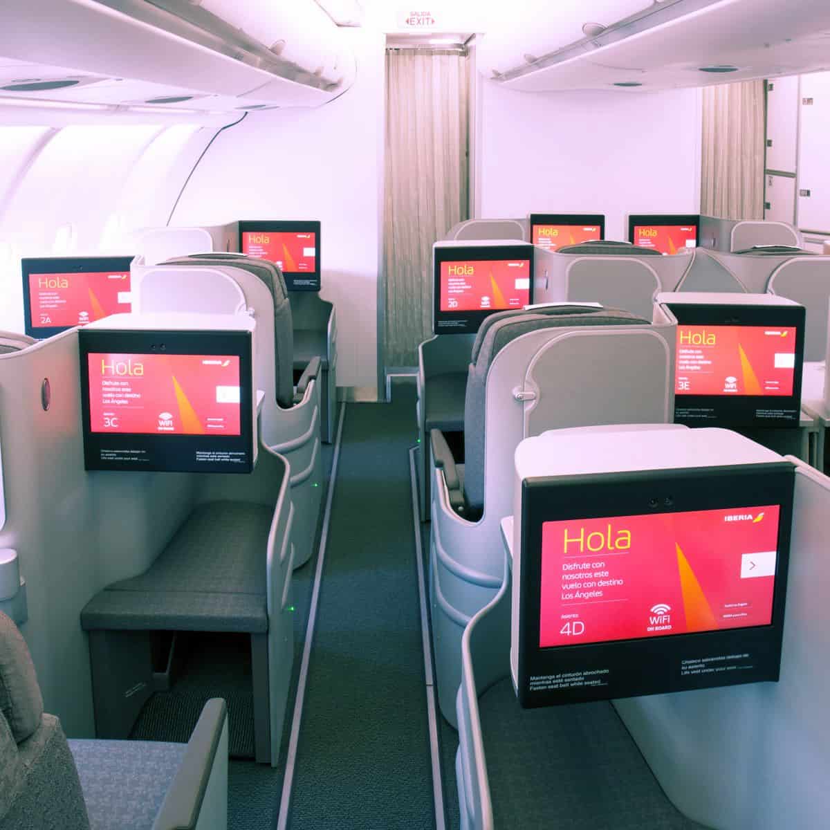 Iberia business class cabin featuring comfortable seats and personal inflight entertainment screens with ambient lighting.