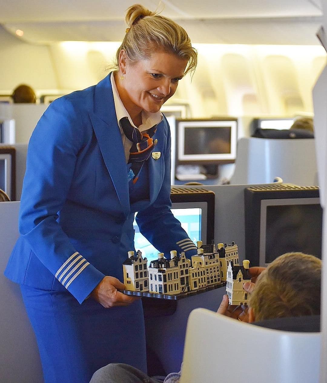 KLM cabin crew offering Delft Blue houses to a business class passenger