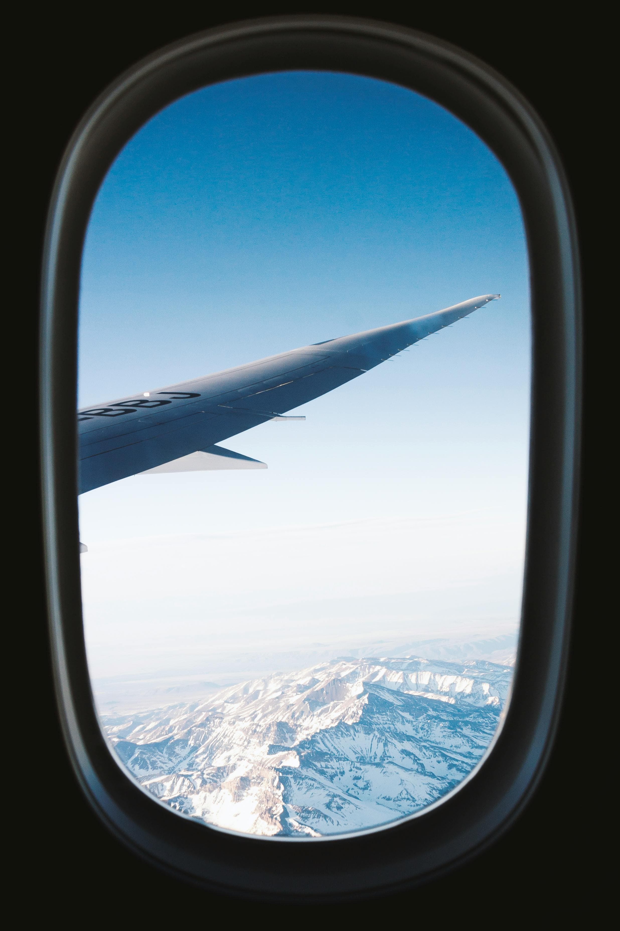 View of the wing and snow-capped mountains from an airplane window